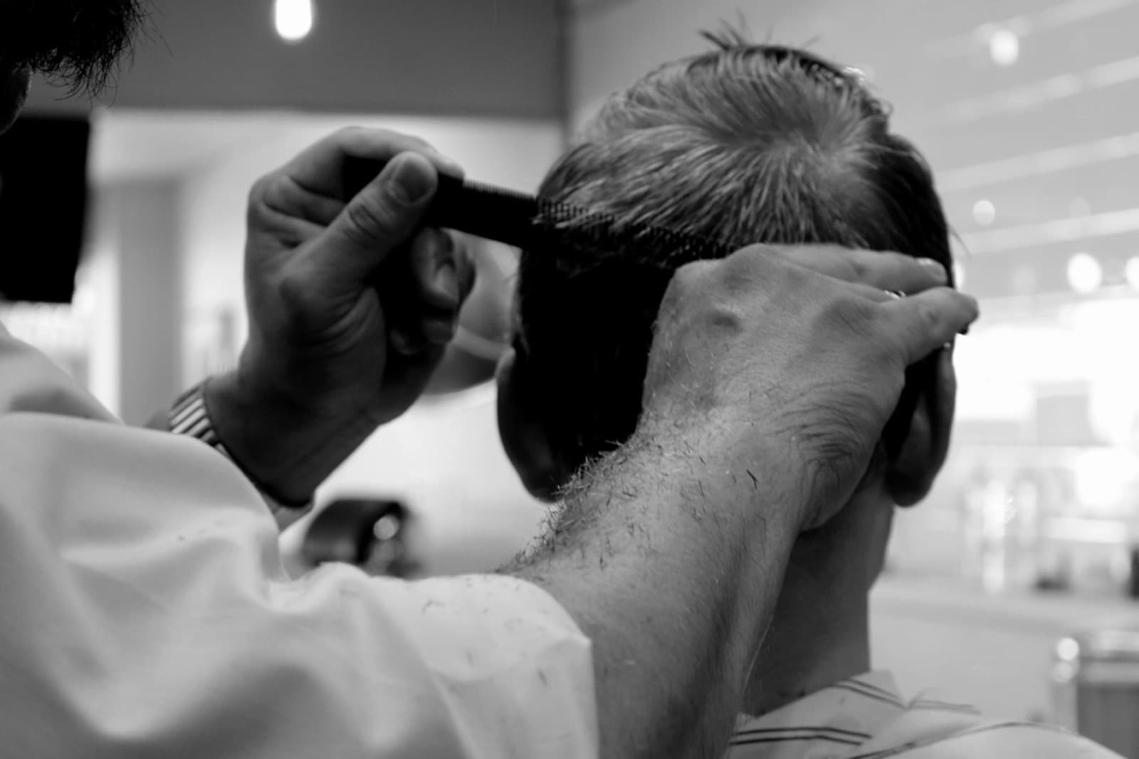 Les mains d'un coiffeur au travail, peigne et ciseaux